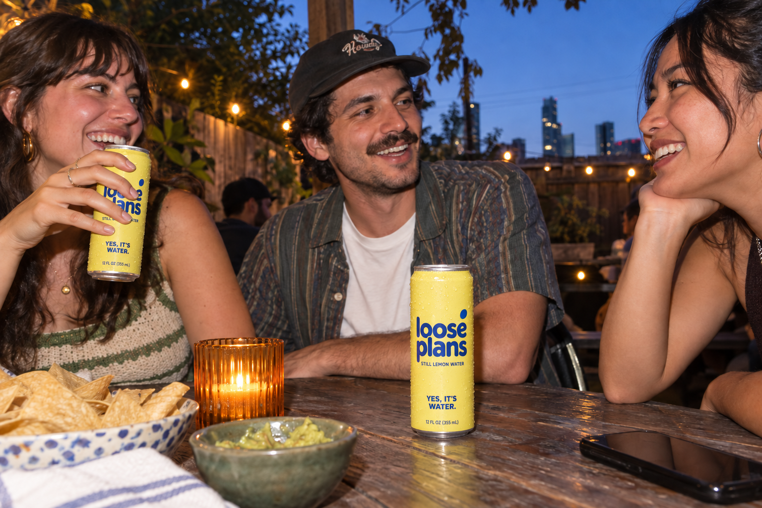 Friends sharing an evening on a patio with Loose Plans cans.
